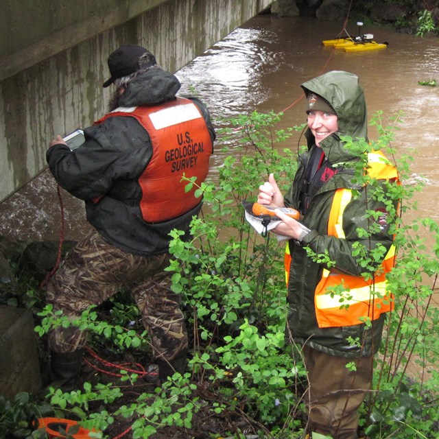 Hydrologists measuring the flow of a fast-flowing stream during a storm