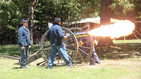 Living historians in period uniforms fire a cannon