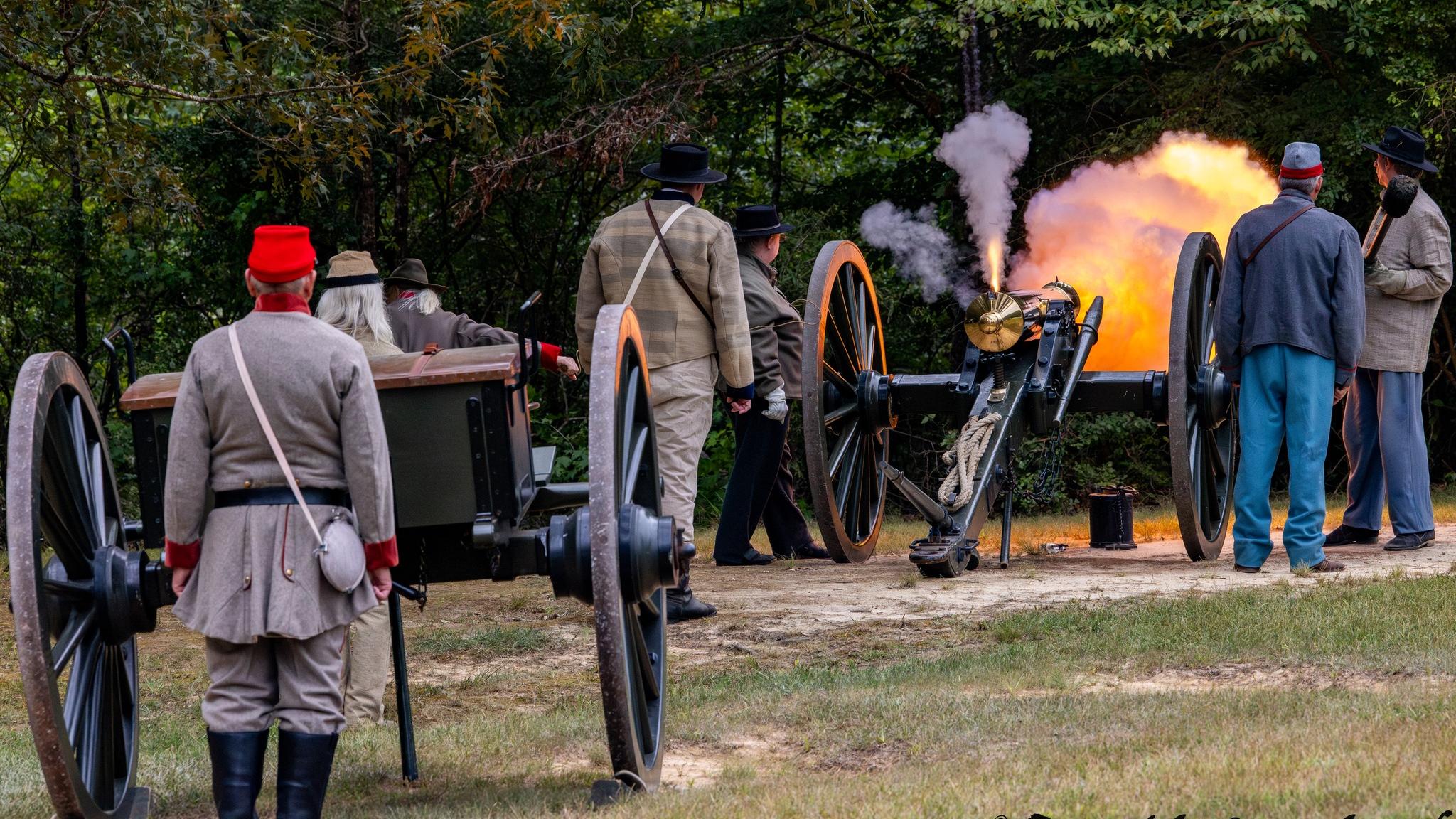 Fire belches from a cannon as living historians present a demonstration.
