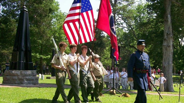 Image of a living historian leading boy scouts as they present the colors. 