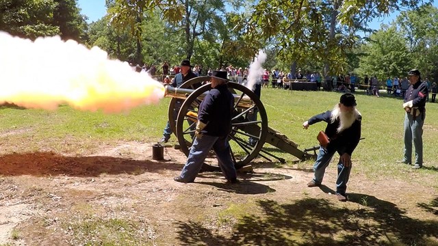 Living historians fire a cannon.