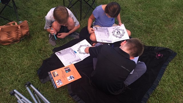Photo of children working on activity books. Below the photo  "Become a Corinth Junior Ranger"