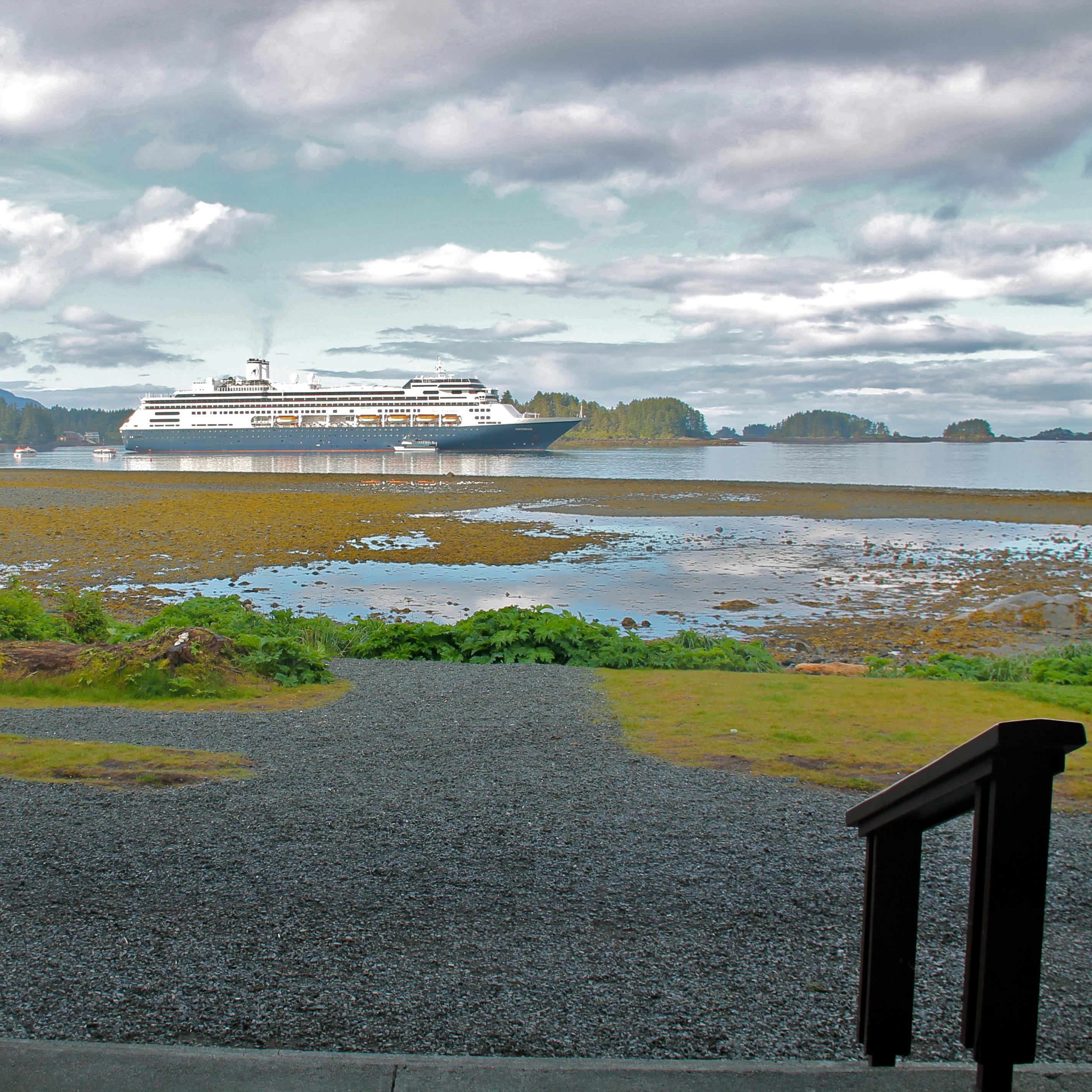 looking from a porch out to the ocean with a cruise ship anchored in the water 