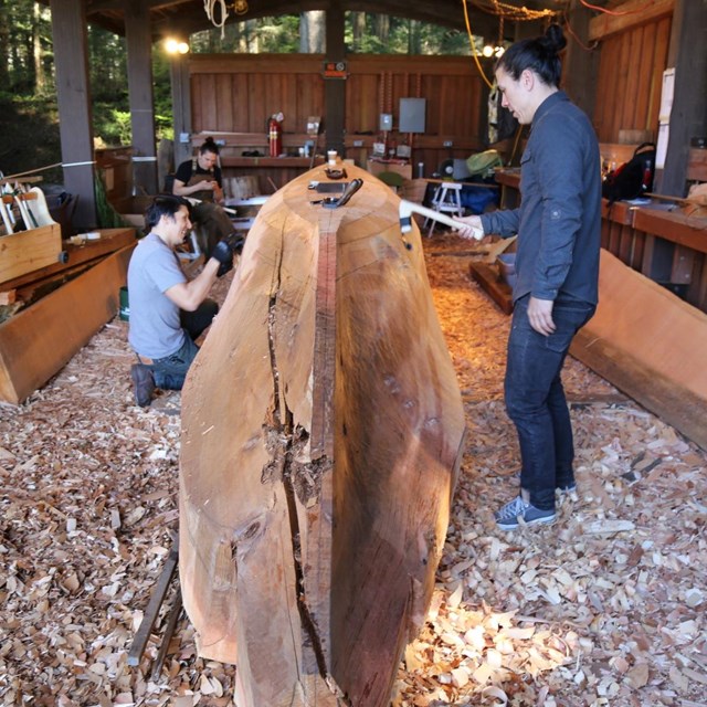 Carvers working on a red cedar log