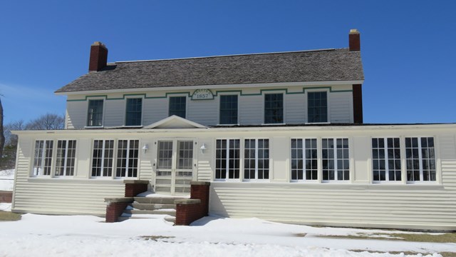 A snow-dusted day, the tall two-story building stands with windows lining the first floor, welcoming