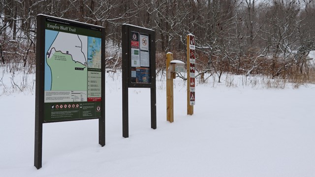 A snowy trailhead with a metal upright map.