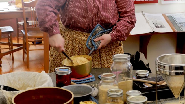 A metal bucket with a funnel running from a tree.