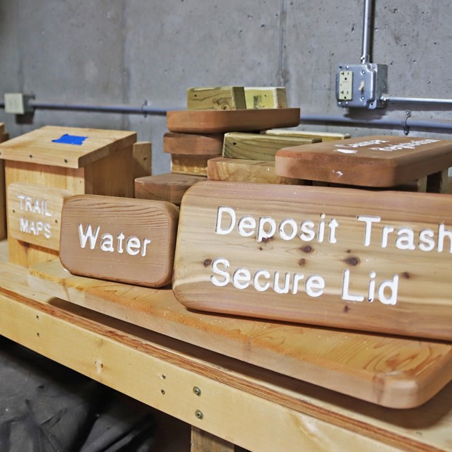 Wooden signs with different text sits on a wooden work table.