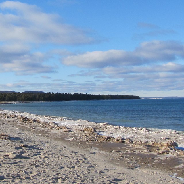 A sandy beach next to a large body of water.
