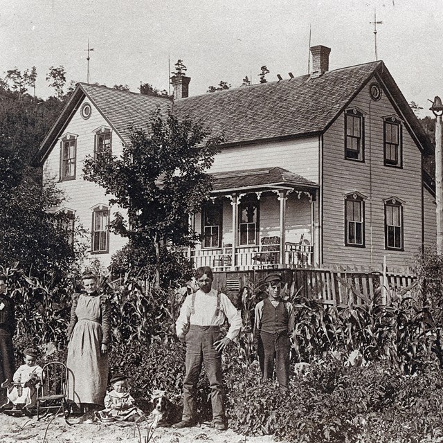 A black and white photo of a historic lumber mill near a creek