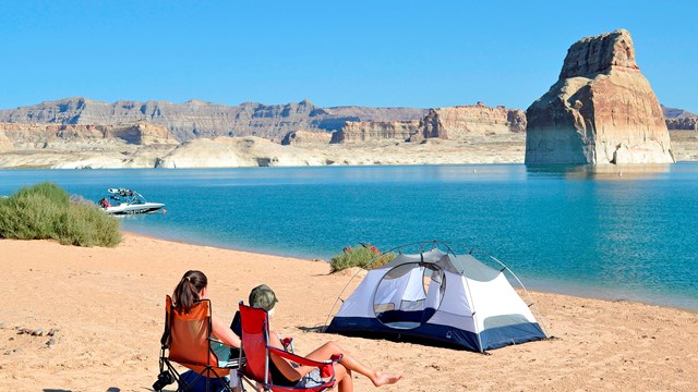 A pair of visitors look over blue waters at their camp site in Glen Canyon