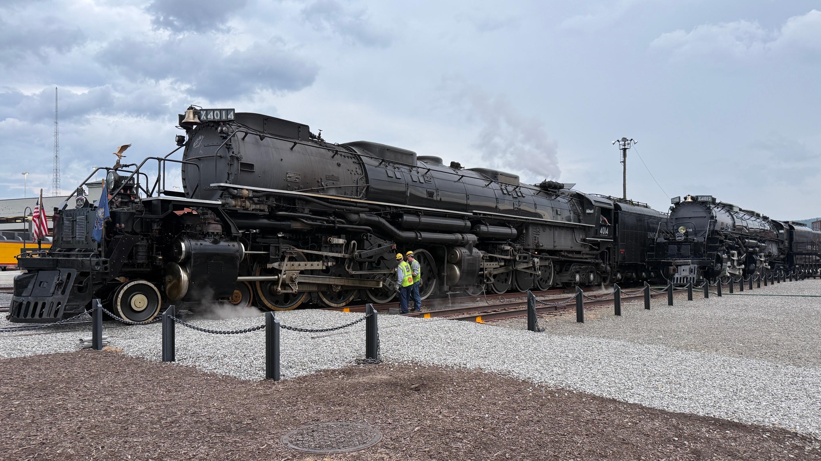 Large steam locomotive steaming through farm fields