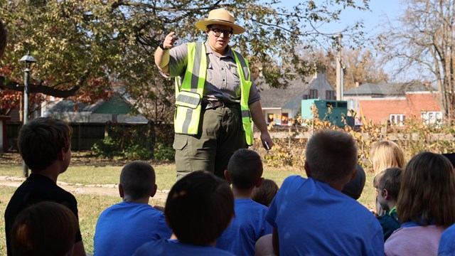 Park Ranger stands in outside talking to a group of students.