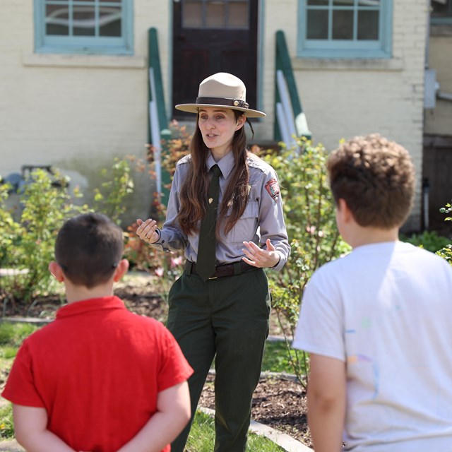 Ranger talks to kids in rose garden to a group of kids.