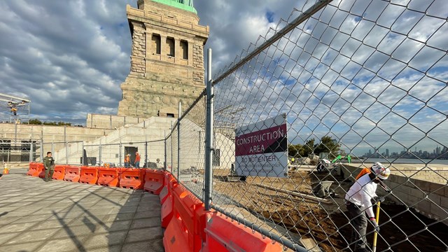 construction workers and barricades on the top of the fort that the statue of liberty stands on.