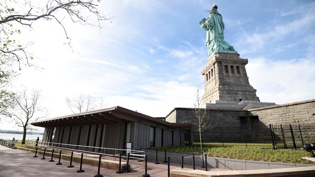 The backside of the Statue of Liberty with a building at the side of it. 