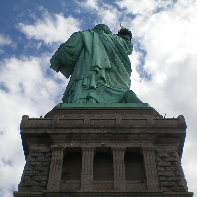 A view of the Statue of Liberty and pedestal from the ground behind the monument.