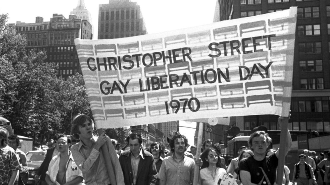 People holding a banner that says "Christopher Street Gay Liberation Day 1970"