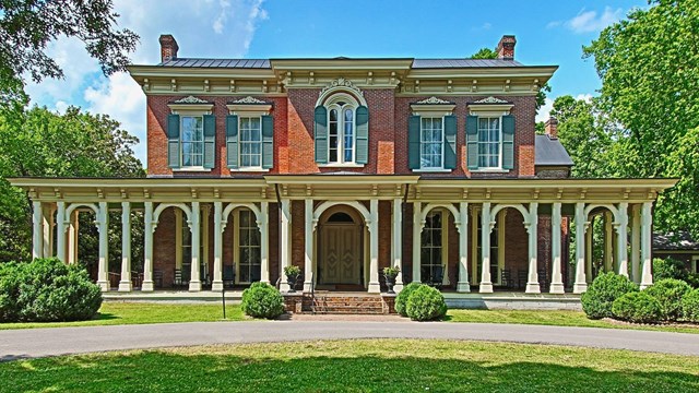 A brick mansion with 7 arches in front of the porch.