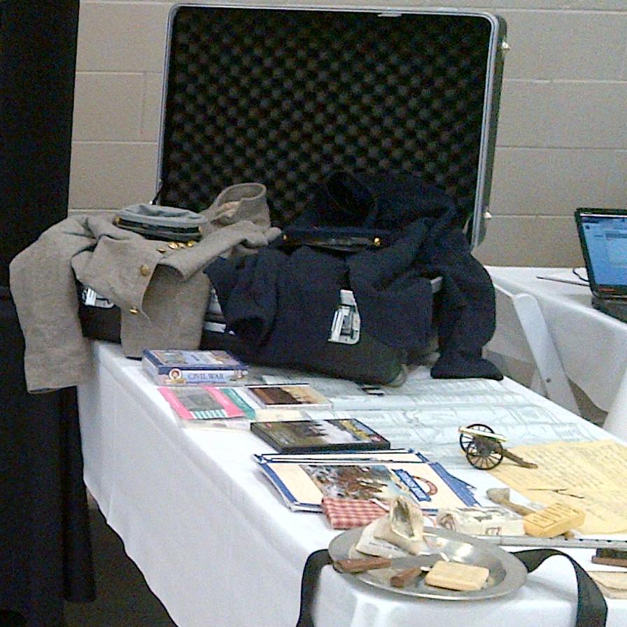 A display board is set up on a pair of tables, with an open trunk on one of them.