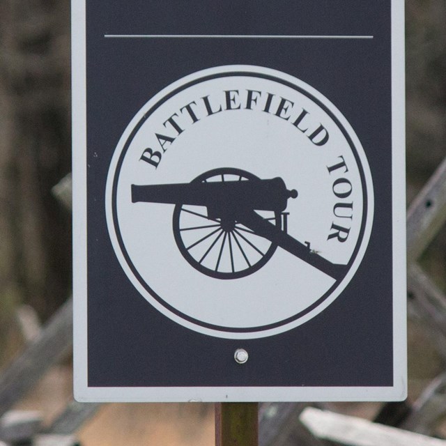 A black and white sign that says Battlefield Tour with the picture of a Civil War cannon in profile.