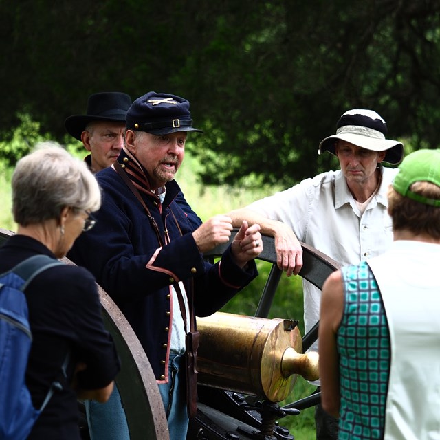 Man dressed as Civil War soldier speaks to visitors in front of cannon