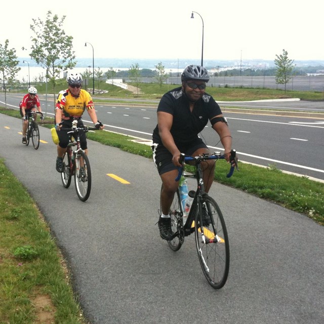 Three cyclists on a paved bike trail. 