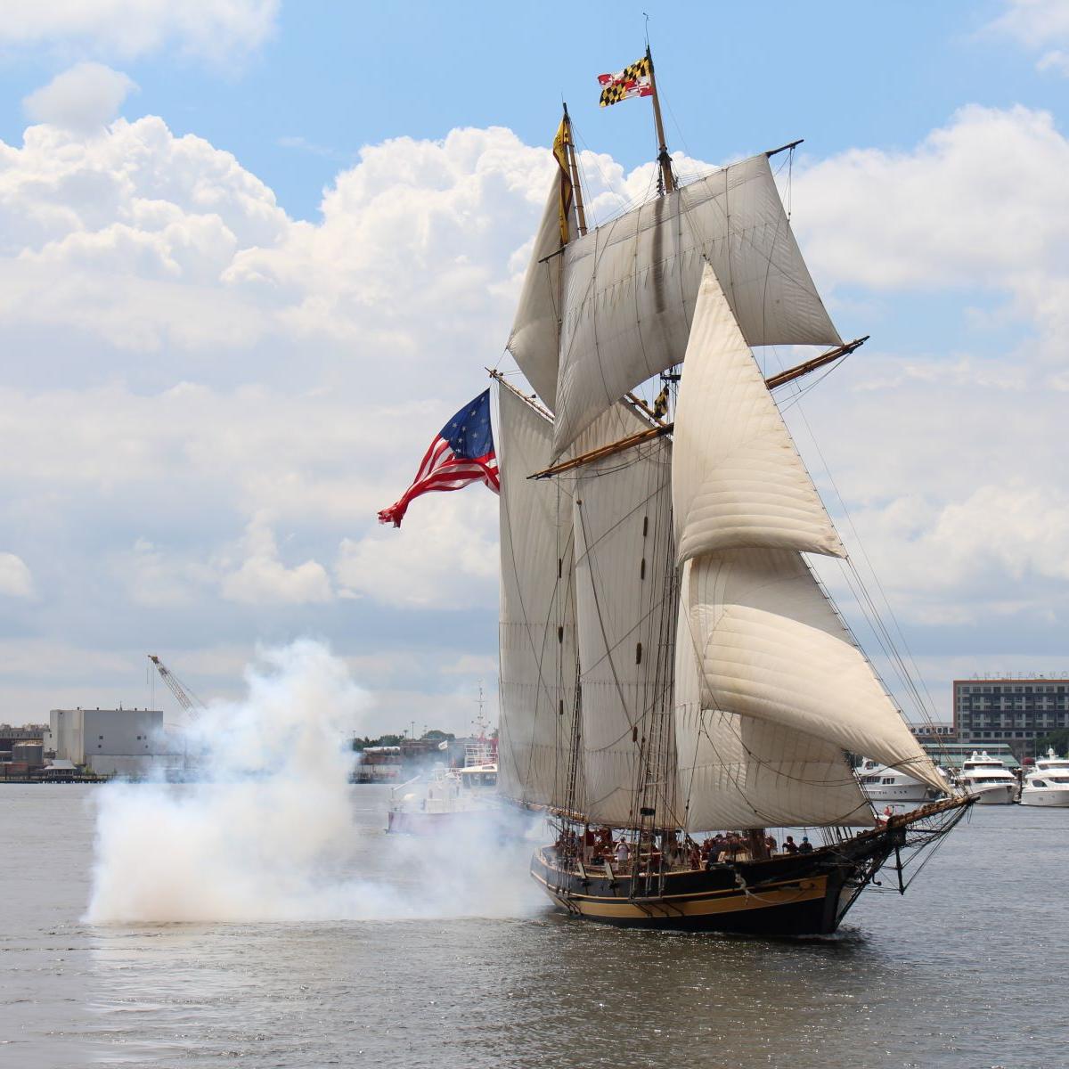 Photograph of a tall ship sailing after firing a cannon.