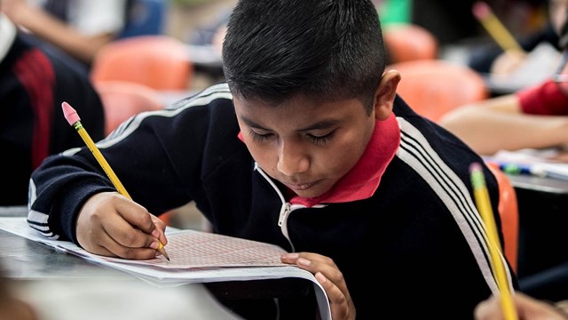 Boy writing with a pencil. 