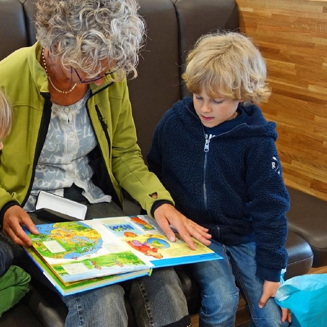 Woman reading book to two kids. 