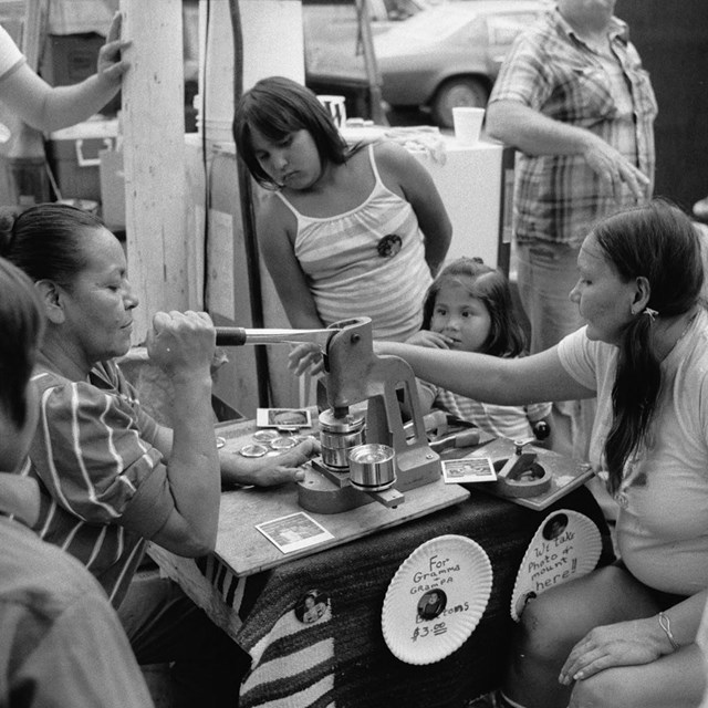 A group of people making buttons at a pow wow. Library of Congress image
