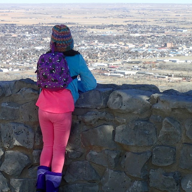 A young hiker stands at the North Overlook, looking down on the town of Scottsbluff.