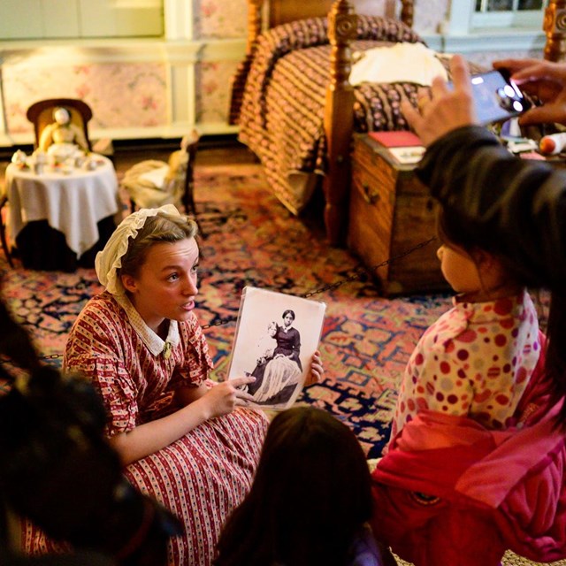 A living historian talking to a crowd holding a picture in the Hampton mansion.