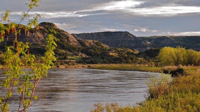 Little Missouri River with green prairies and tall buttes.