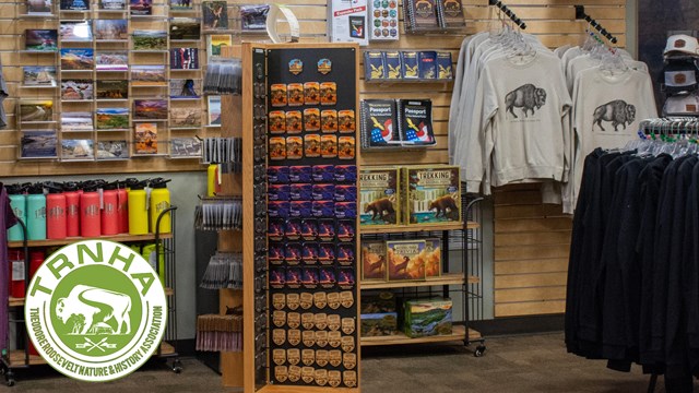 Two people browse various items in a store; white and green logo displayed in bottom right corner. 