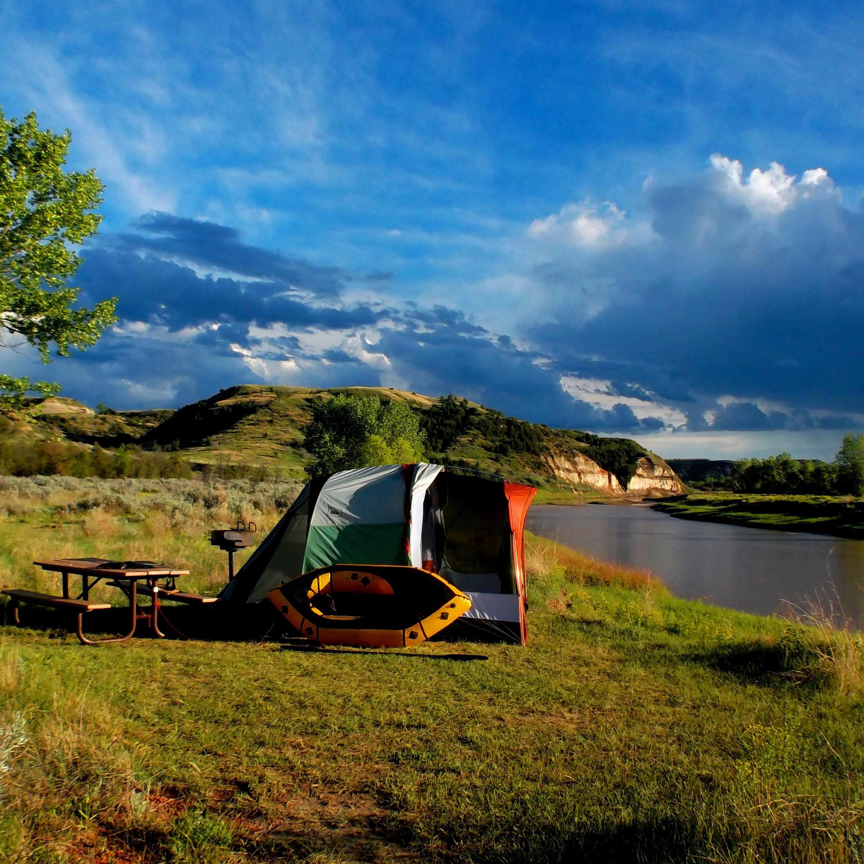 A tent with inflatable canoe on the edge of the Little Missouri River.