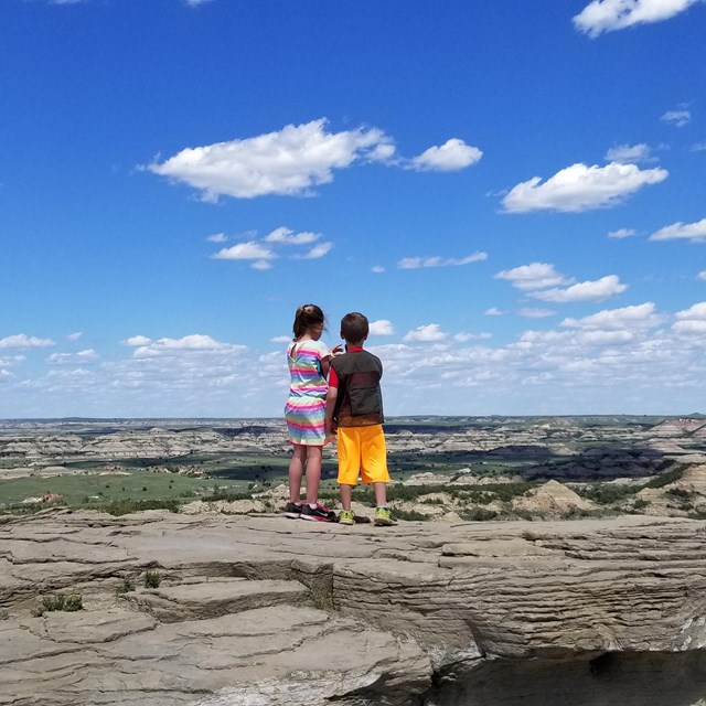 Two children look out into the badlands from an overlook.