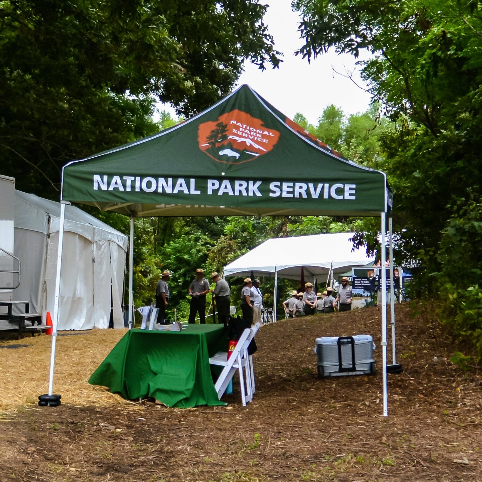 NPS tents and a historical marker sit in a grassy area