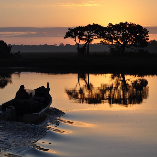 boat heading out to the marsh at dawn 