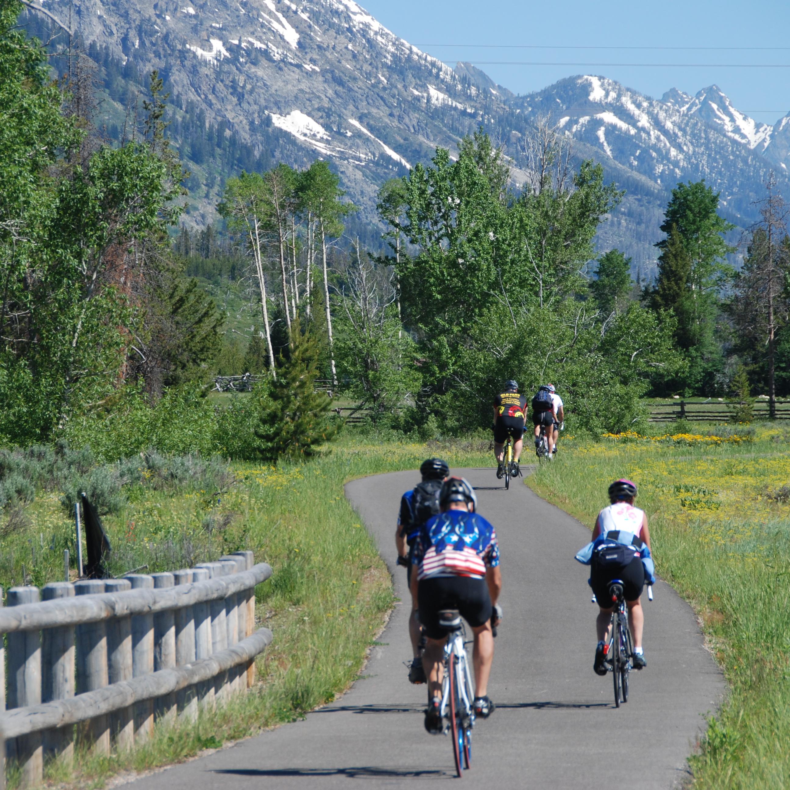 Riding bikes on paved path with the Grnad Teton mountains in the back