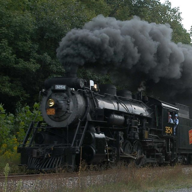 an old black locomotive, smoke coming out of the top