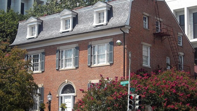 Photo of three-story brick house. 