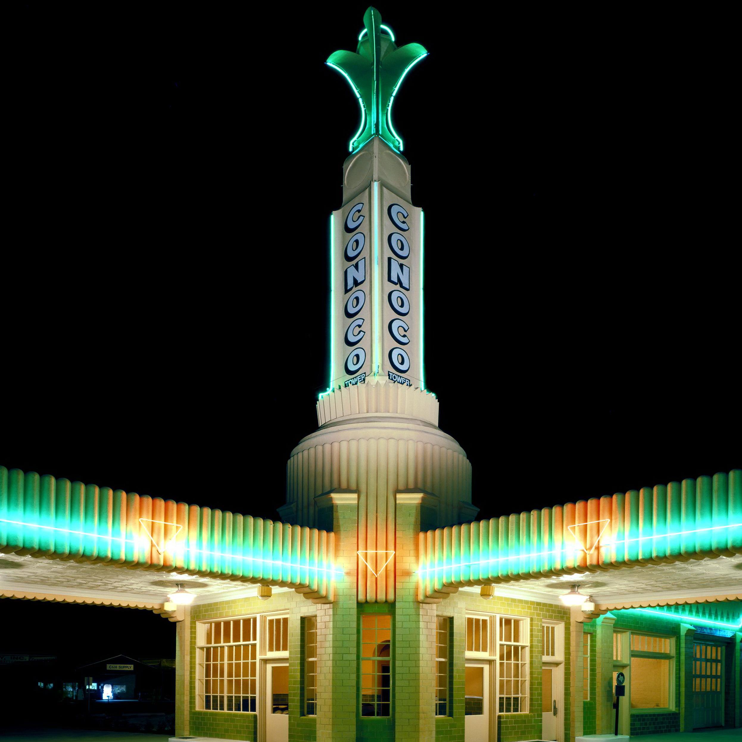 A historic gas station, lit up in neon lights at night.