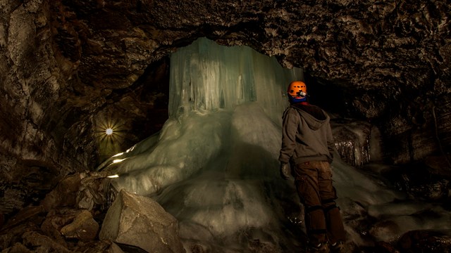Ranger in a cave standing in front of ice. NPS Photo Jesse Barden