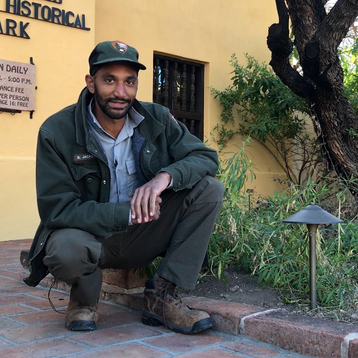 Park ranger squatting next to a shielded light fixture on front walkway