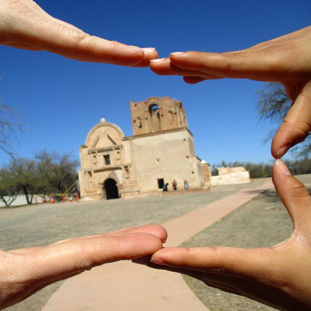 Hands framing a historical structure.