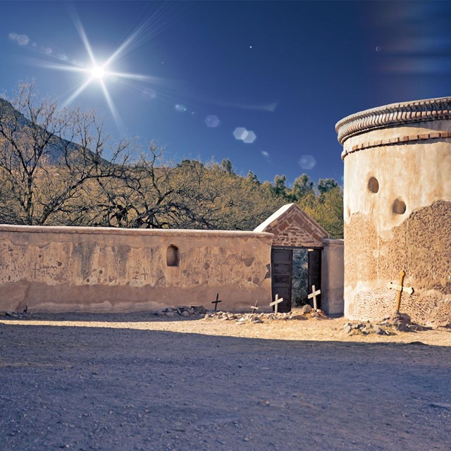 Photograph of mortuary chapel and cemetery with sun rays overhead.