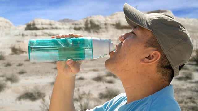 A man takes a drink from a water bottle