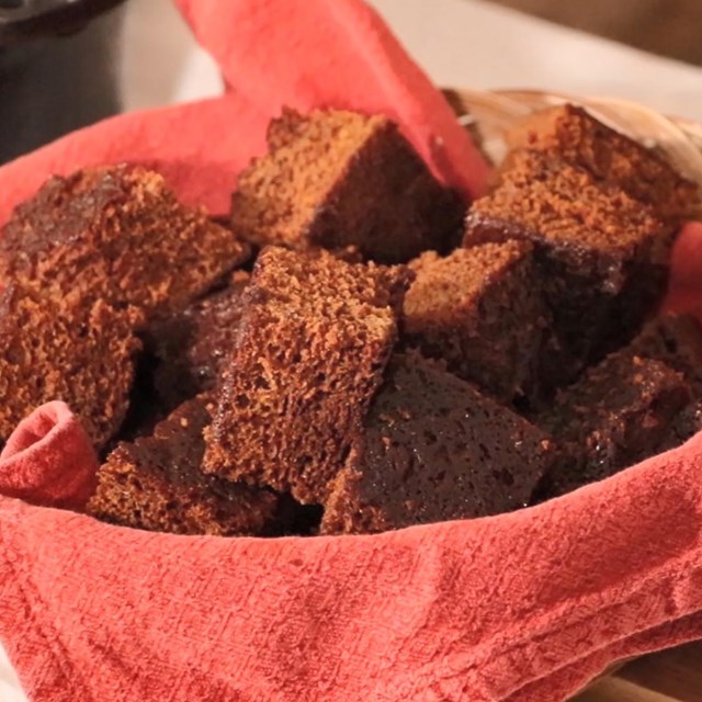 Fluffy brown ginger cake fills a woven basket lined with a red cloth. 