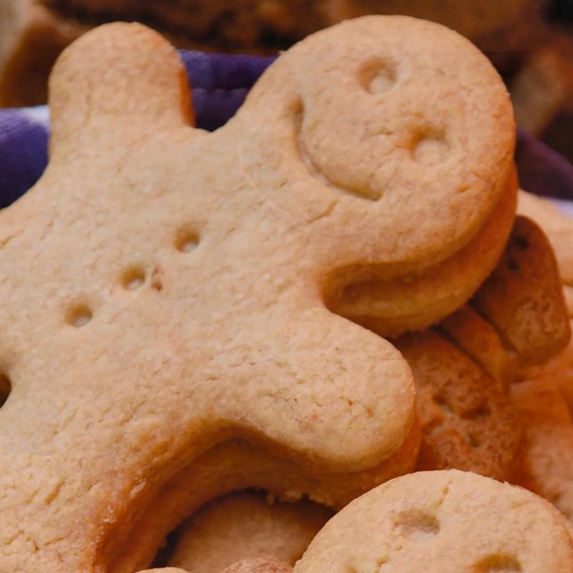 Gingerbread men fill a basket lined with a blue checkered cloth. 
